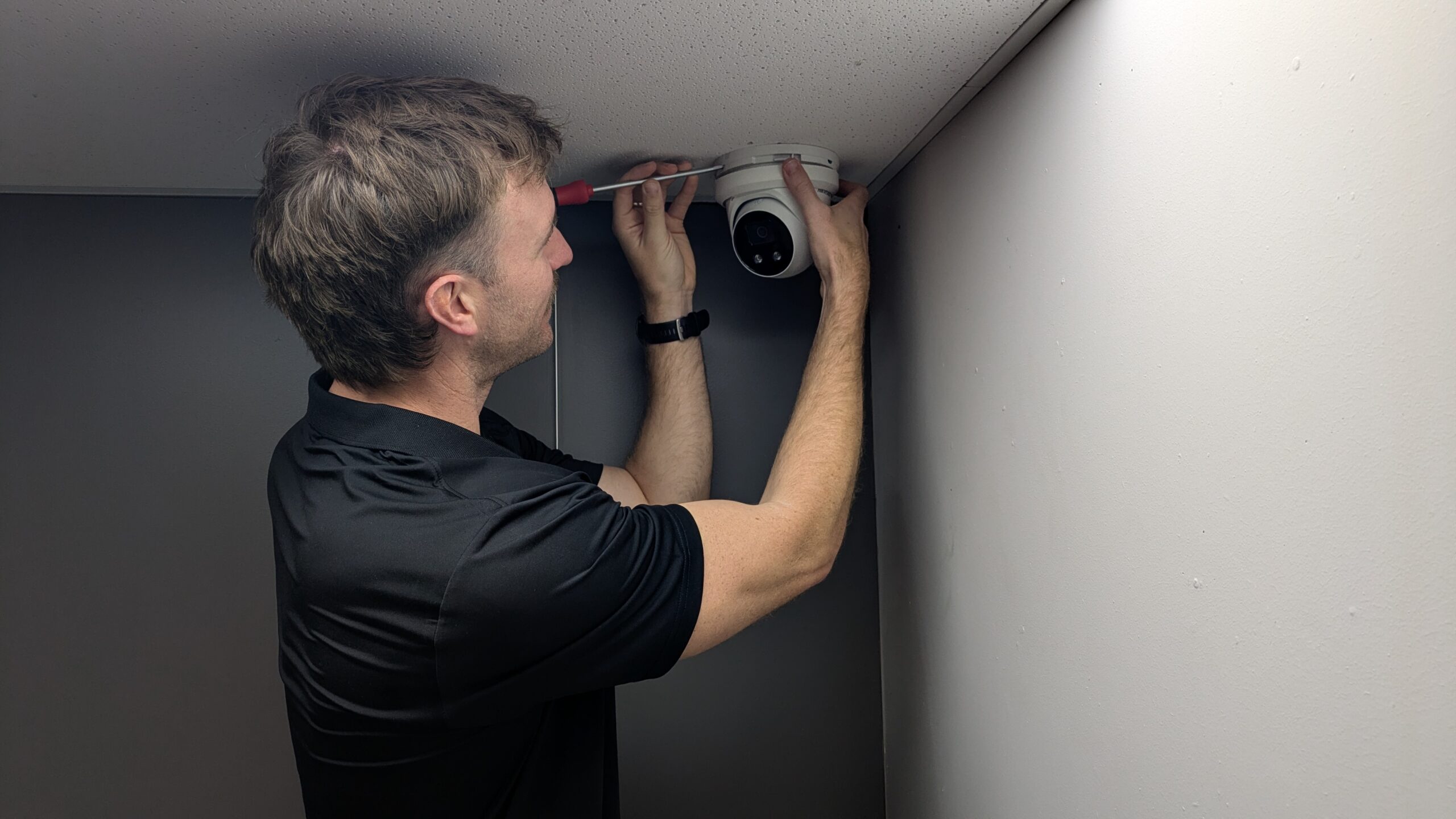 security expert attaching CCTV camera to office ceiling